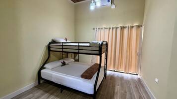 Habitación con literas, techo de madera, aire acondicionado y ventana con cortinas.