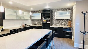 A modern kitchen with a large island, black bar stools, and a black and white tiled backsplash. - 3Bed+2Bath Steam Sauna Retreat in Vancouver! Family friendly! (Vancouver)