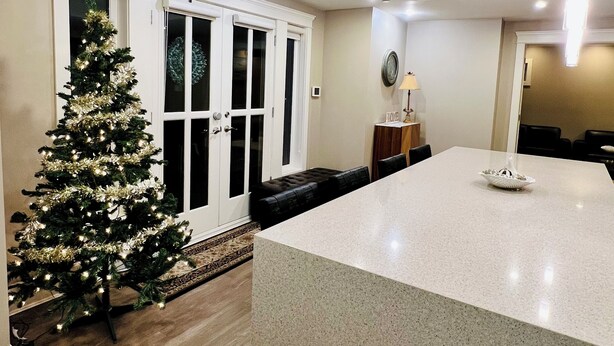 A modern kitchen with a large island, a Christmas tree, and a dining area with a bench. - 3Bed+2Bath Steam Sauna Retreat in Vancouver! Family friendly! (Vancouver)