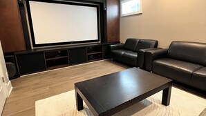 A modern home theater room with a large screen, leather seating, and a coffee table. - 3Bed+2Bath Steam Sauna Retreat in Vancouver! Family friendly! (Vancouver)