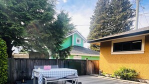 A wooden deck with a bench and table, surrounded by a wooden fence and a house in the background. - 3Bed+2Bath Steam Sauna Retreat in Vancouver! Family friendly! (Vancouver)