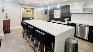 A modern kitchen with a large island, bar stools, stainless steel appliances, and pendant lighting. - 3Bed+2Bath Steam Sauna Retreat in Vancouver! Family friendly! (Vancouver)