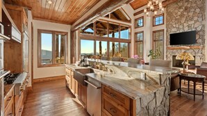 A spacious kitchen with a large island, wooden cabinetry, and a stone accent wall.