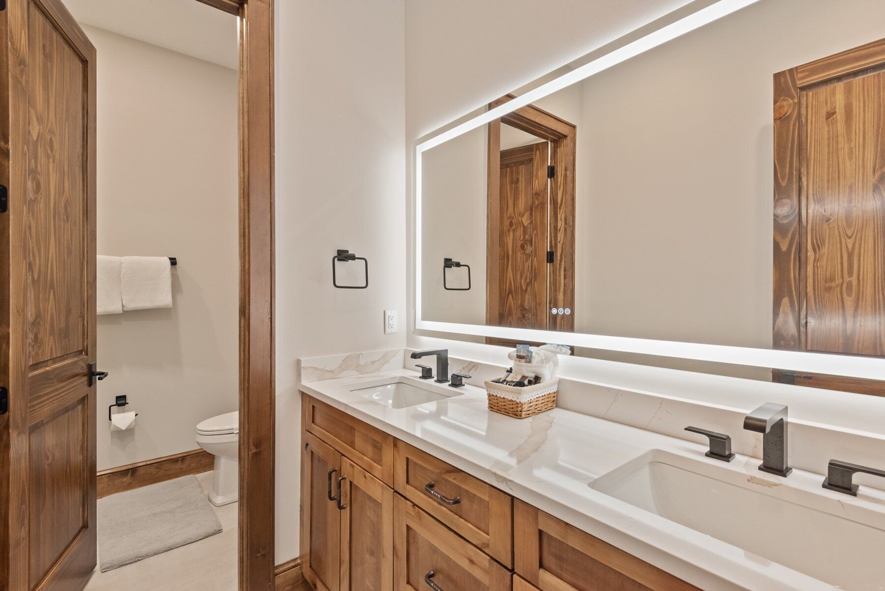 A bathroom with a wooden vanity, a large mirror, and a white sink.