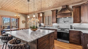 A spacious kitchen with a large island, wooden cabinets, and a stainless steel stove. - Rock Haven at Eagles Nest - pets, views, four king beds, hot tub (Banner Elk)