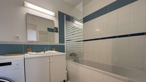 A modern bathroom with a washing machine, a sink, and a bathtub.