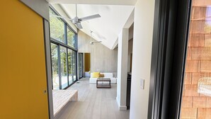 A modern interior with a long hallway, large windows, and a ceiling fan. - Cape Cod Bay Views | 2BR/2BA Eastham, Modern, EV (Eastham)