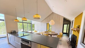 A modern kitchen with a central island, stainless steel appliances, and pendant lighting. - Cape Cod Bay Views | 2BR/2BA Eastham, Modern, EV (Eastham)