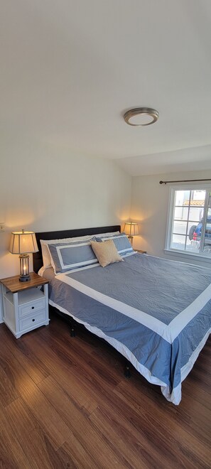 Relax in this serene bedroom with a large bed, two bedside tables, and a window offering a view of the outside.