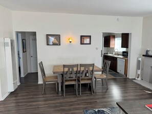 Enjoy meals in this stylish dining area with a wooden table and chairs, surrounded by framed artworks and a sleek kitchen.