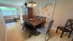 A dining area with a wooden table, six chairs, and a world map on the wall. - Your Home in Sandy – Comfortable, Convenient & Affordable (Sandy)