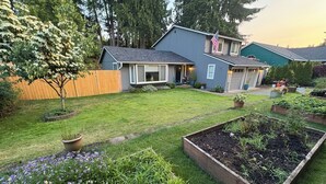 A residential property with a well-maintained lawn, raised garden beds, and a wooden fence. - Your Home in Sandy – Comfortable, Convenient & Affordable (Sandy)