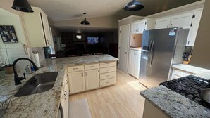A kitchen with a granite countertop, stainless steel appliances, and a skylight. - Your Home in Sandy – Comfortable, Convenient & Affordable (Sandy)