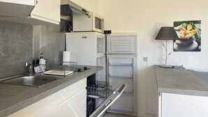 A compact kitchen with a built-in dishwasher, a microwave, and a refrigerator.