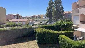 A residential area with apartment buildings, a parking lot, and well-maintained hedges.