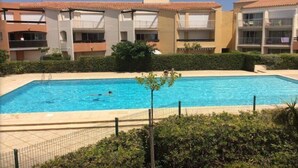 A swimming pool surrounded by apartment buildings with balconies.