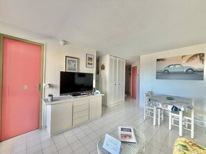 Um espaço compacto com televisão, mesa de jantar e cozinha.