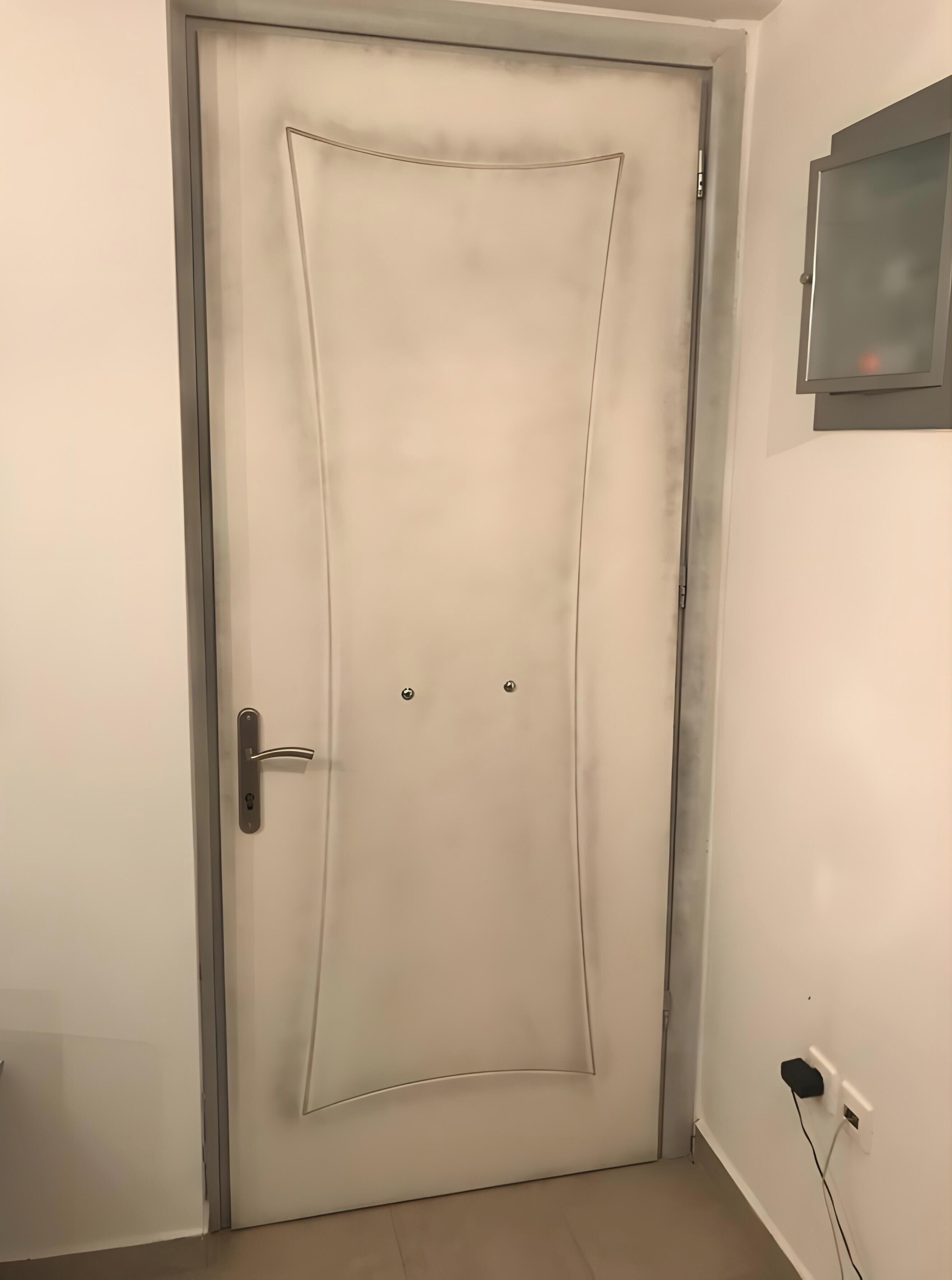 A door with a handle and two screws, a power outlet, and a wall-mounted object.
