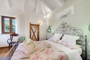 Ein Schlafzimmer mit Bett, Stuhl, Holztür, Wandleuchte und Fenster mit Blick.