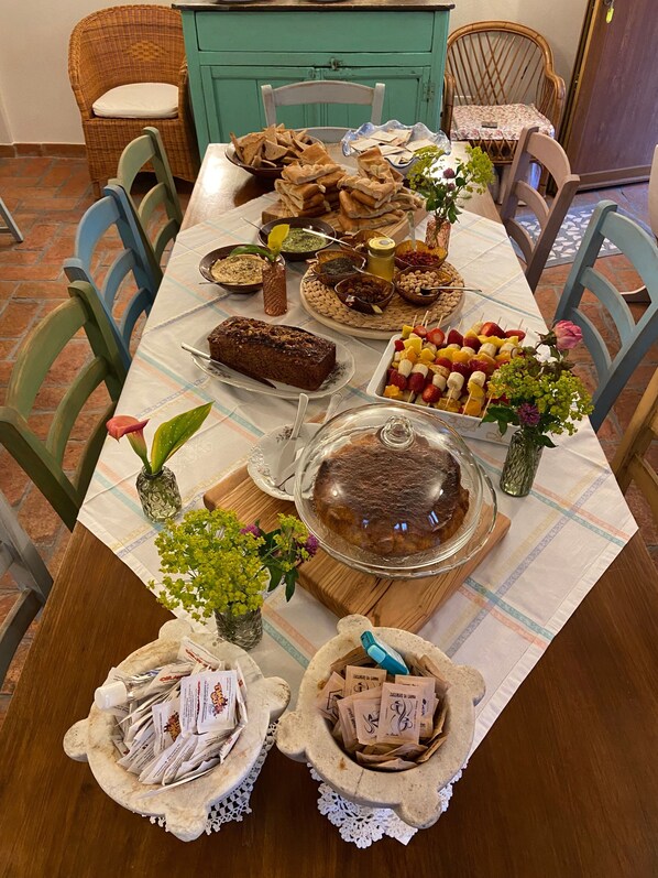 Una mesa de comedor con diferentes alimentos, un pastel y flores decorativas.