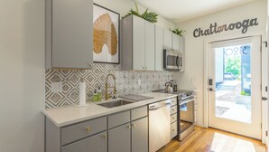 Una cucina moderna con mobili grigi, un forno a microonde in acciaio inossidabile e uno schienale decorato.