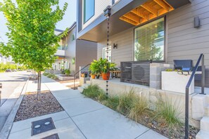 A modern building with a covered outdoor seating area, potted plants, and a tree. - Cozy 1-bedroom condo in Historic St. Elmo Chattanooga with Mountain Views (Chattanooga)
