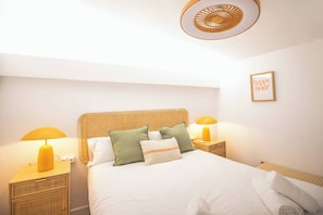 A neatly arranged bedroom with a large bed, two bedside tables with lamps, and a ceiling fan.