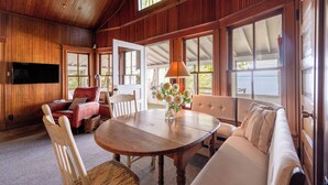 A wooden interior with a round table, two sofas, and a TV mounted on the wall.