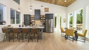 A modern kitchen with a central island, dark cabinets, and a stainless steel refrigerator. - Back Deck with a View - Games - Pets - Hickory Pines (Broken Bow)