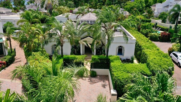 A white villa with a central courtyard surrounded by lush greenery and palm trees. - Tropical Holiday Rental Villa - Villatre (Mullins)