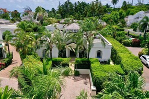 A white villa with a central courtyard surrounded by lush greenery and palm trees.