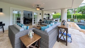 A covered outdoor living area with wicker furniture, a ceiling fan, and a pool. - Tropical Holiday Rental Villa - Villatre (Mullins)