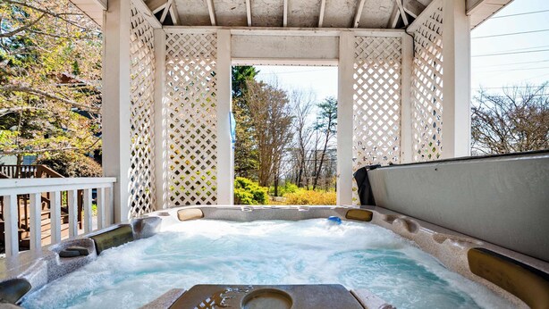 A hot tub with a label 'Land Spas' in a covered outdoor area with lattice panels and a view of trees. - Chattanooga Cottage with Free Breakfast (Lookout Mountain)
