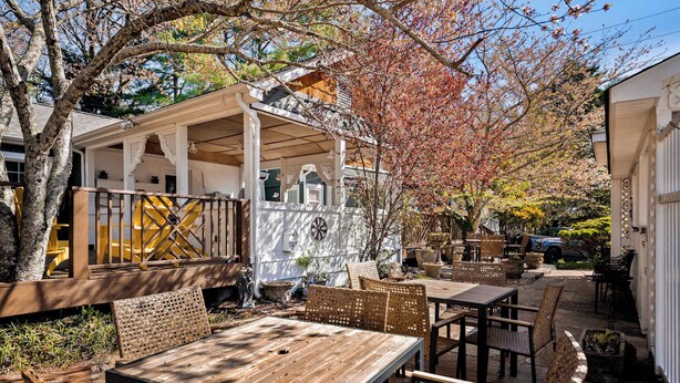 Une terrasse en bois avec des meubles d’extérieur, un espace salon couvert et un jardin.