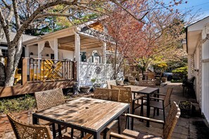 Eine Holzterrasse mit Gartenmöbeln, einer überdachten Sitzgruppe und einem Garten.