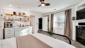 A bedroom with a bed, a ceiling fan, a kitchen area with a microwave, and a fireplace. - Sequatchie Cottage on Lookout Mountain (Lookout Mountain)