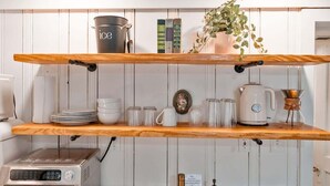 A kitchen with wooden shelves holding kitchenware, a coffee maker, and a kettle. - Sequatchie Cottage on Lookout Mountain (Lookout Mountain)