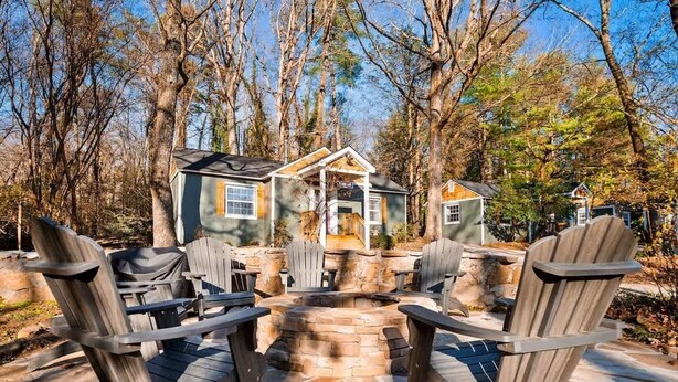 A cabin with a stone fire pit, surrounded by Adirondack chairs, set in a wooded area. - Sequatchie Cottage on Lookout Mountain (Lookout Mountain)