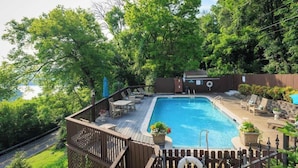 A backyard with a swimming pool, deck chairs, and a small shed.