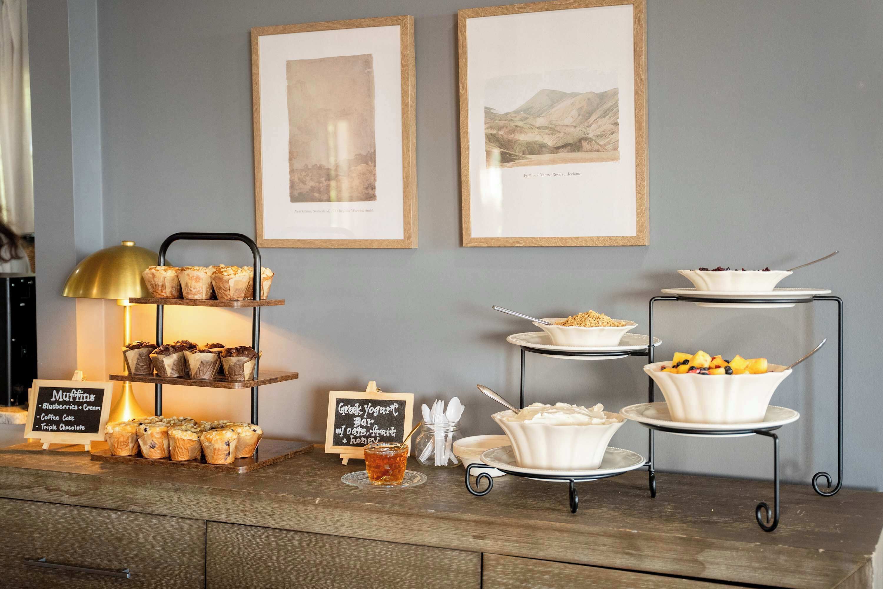 A buffet setup with muffins, yogurt, and fruit bowls.