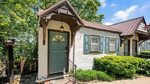 A quaint building with a stone entrance, a green door, and a small porch with a lantern.