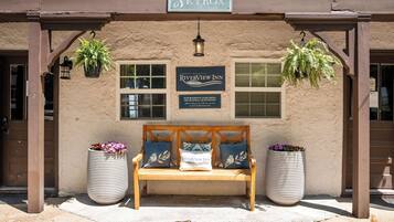 A bench with a sign for Riverview Inn, a hanging lantern, and two potted plants.