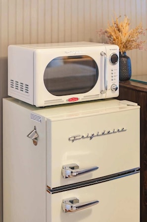 A retro-style refrigerator with a microwave on top.