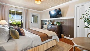 A bedroom with a bed, a television, a desk, and a chair. - Historic Riverview Inn - King Room Three (Chattanooga)