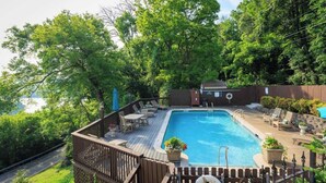 A swimming pool with a deck, surrounded by trees and a wooden fence. - Historic Riverview Inn - King Room Three (Chattanooga)