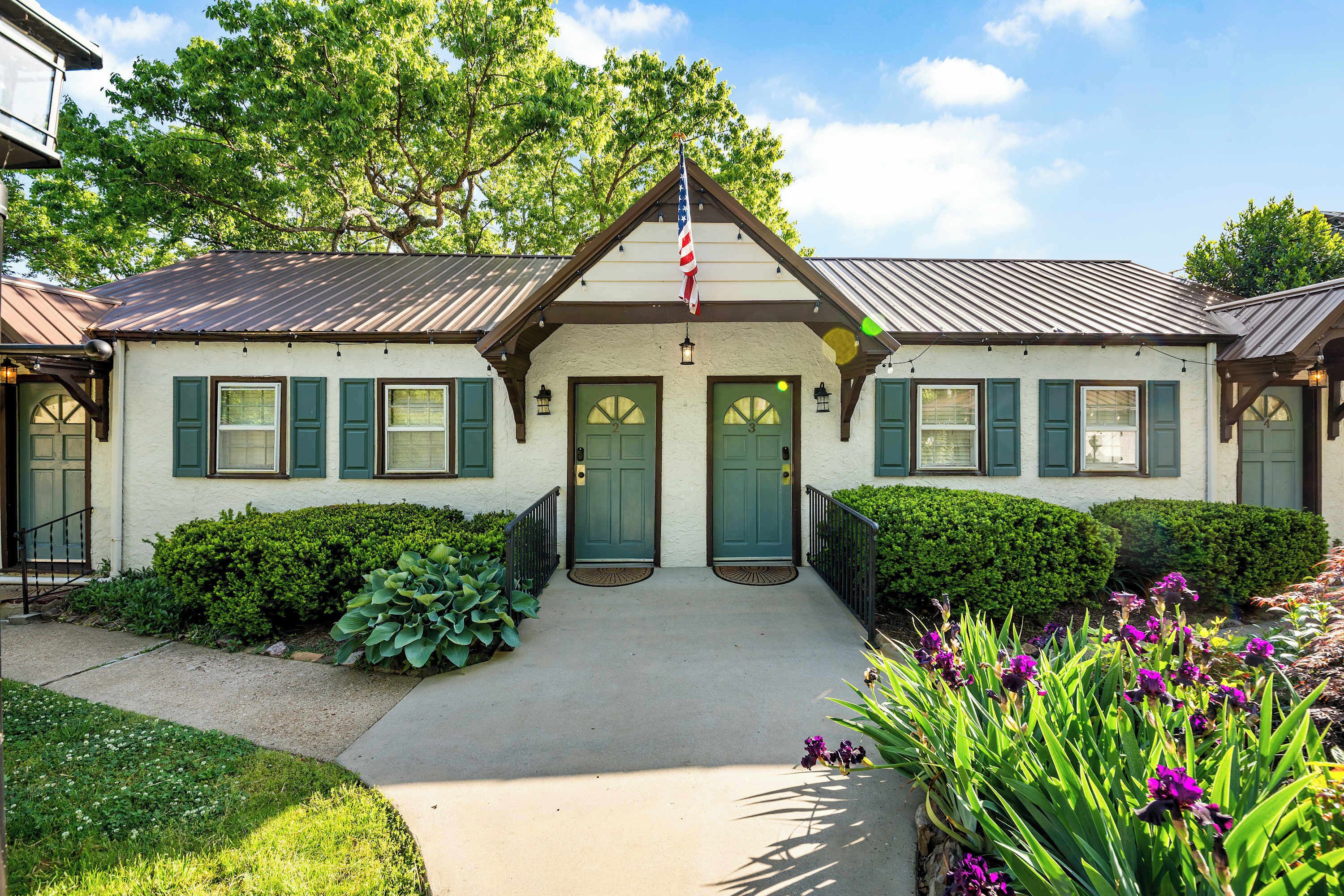 A two-story building with a symmetrical facade, green shutters, and a central entrance with double doors.