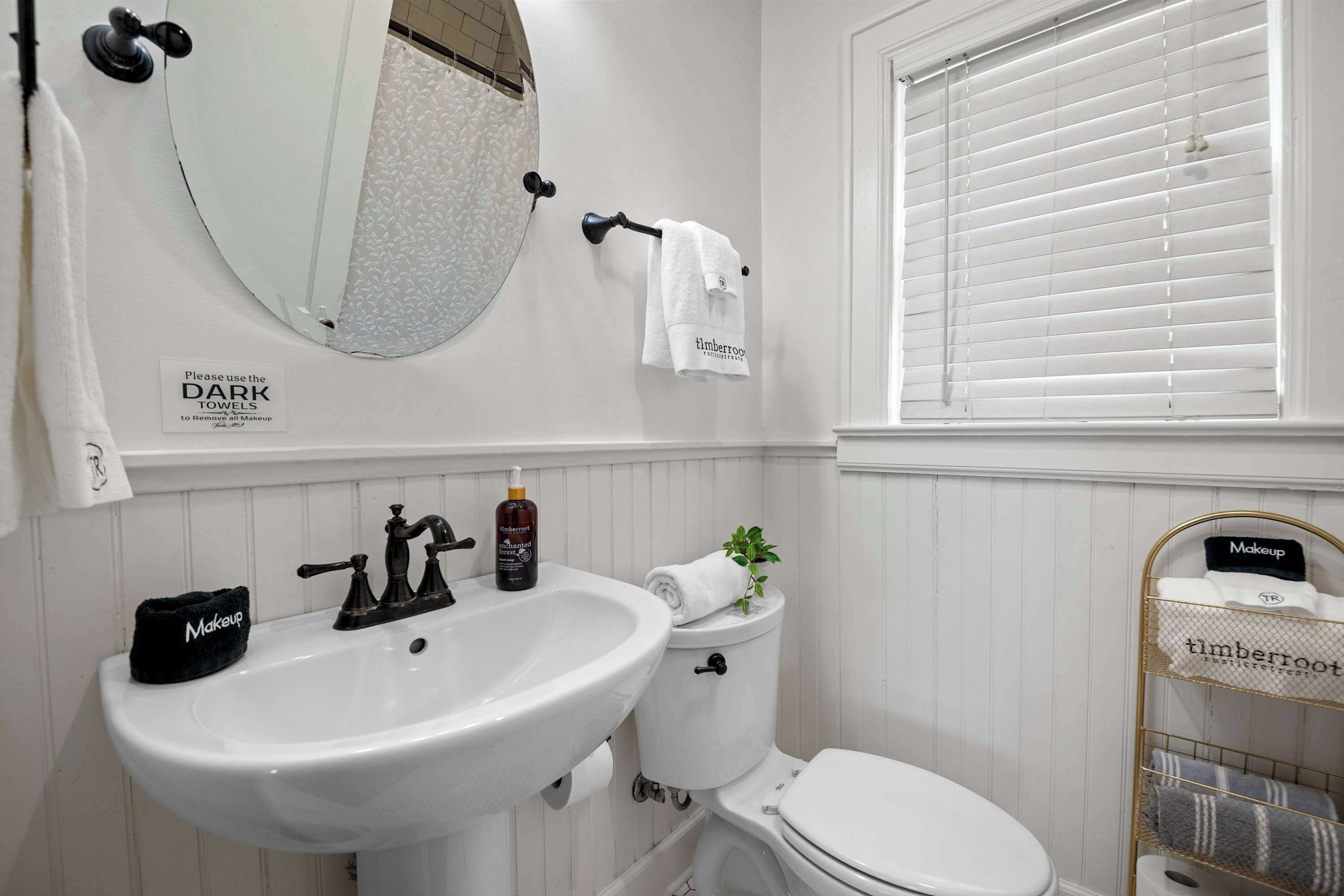 Une salle de bain avec un lavabo blanc, des toilettes, un miroir et un porte-serviettes.