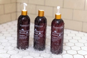 Drei Flaschen Timberroot Enchanted Forest Shampoo und Conditioner auf einer gefliesten Oberfläche.