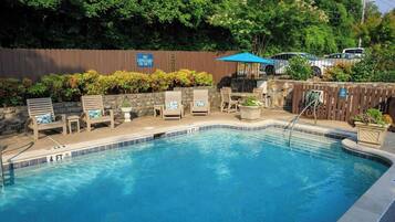 A swimming pool with lounge chairs and a 'No Lifeguard on Duty' sign.