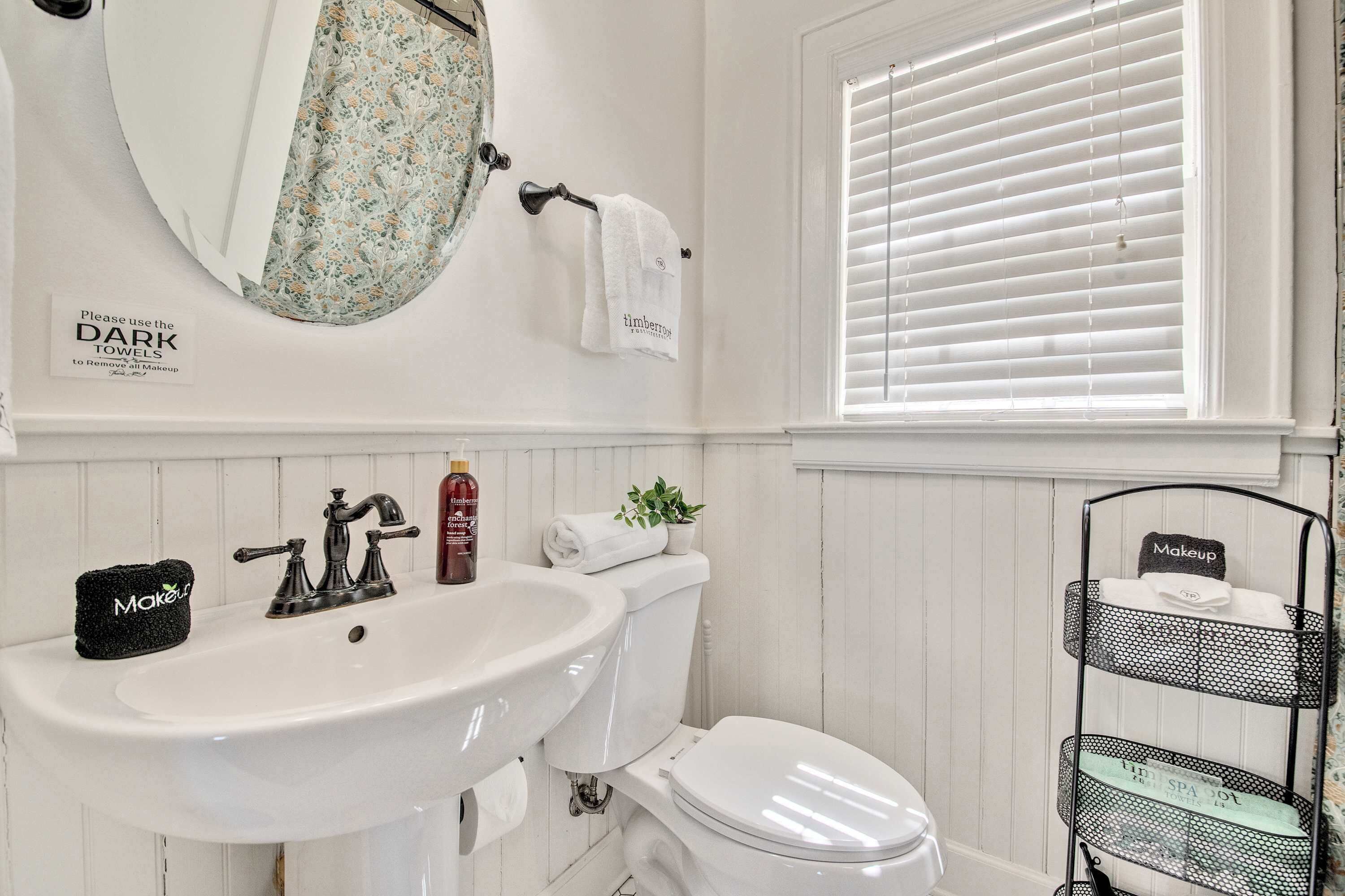 Une salle de bain équipée d’un lavabo, de toilettes et d’un porte-serviettes sur lequel est posée une serviette à motifs floraux.
